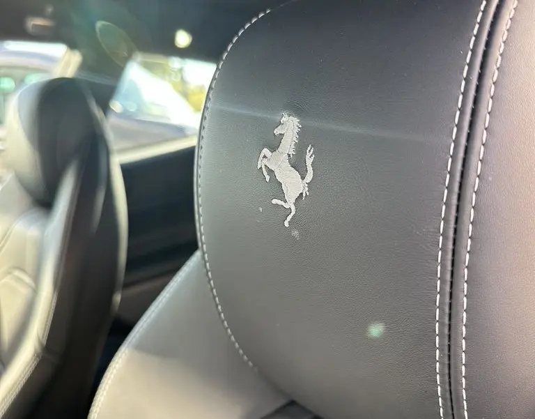 Gros plan sur l'appui-tête en cuir noir avec le cheval cabré brodé à l'intérieur d'une Ferrari GTC4 Lusso 2017.