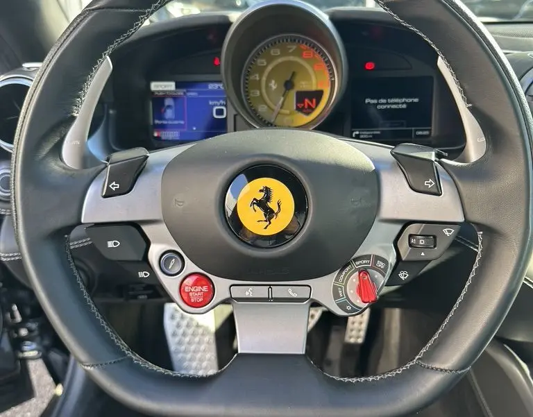 Vue rapprochée du volant noir de la Ferrari GTC4 Lusso 2017 avec logo jaune et tableau de bord digital.