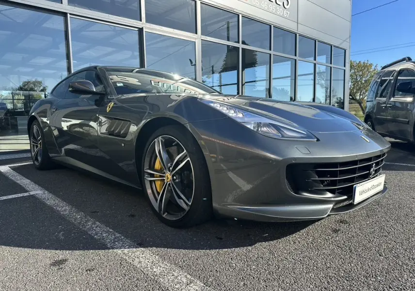 Ferrari GTC4 Lusso gris foncé vue 3/4 avant droit, avec jantes sport et étriers de frein jaunes visibles.