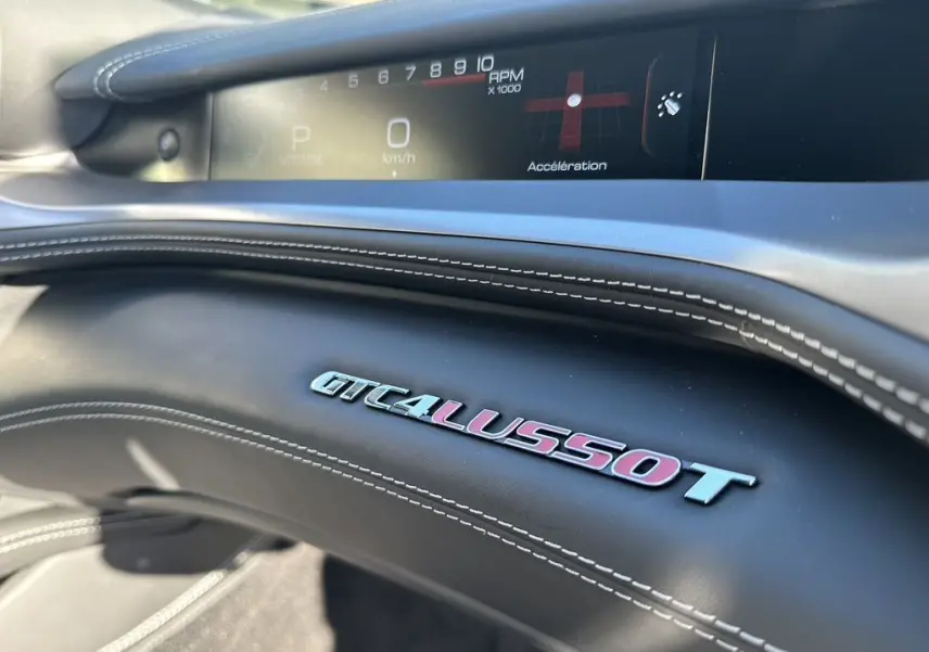 Détail intérieur du tableau de bord de la Ferrari GTC4 Lusso T 3.9 V8, avec logo et affichage numérique du compte-tours.