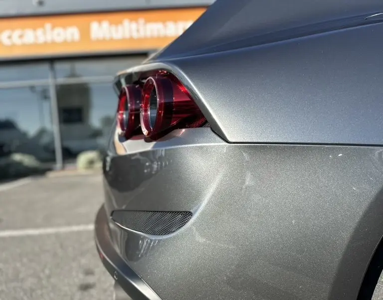 Vue 3/4 arrière droit d'une Ferrari GTC4 Lusso gris foncé mettant en valeur ses feux ronds et lignes fluides.