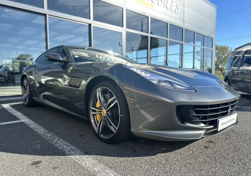 Ferrari GTC4 Lusso gris foncé vue 3/4 avant droit, jantes sport et étriers de frein jaunes visibles.