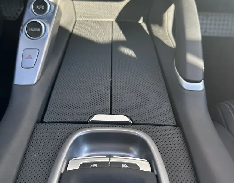 Gros plan sur la console centrale noire perforée de la Ferrari GTC4 Lusso 2017 avec boutons de commande et finition cuir.