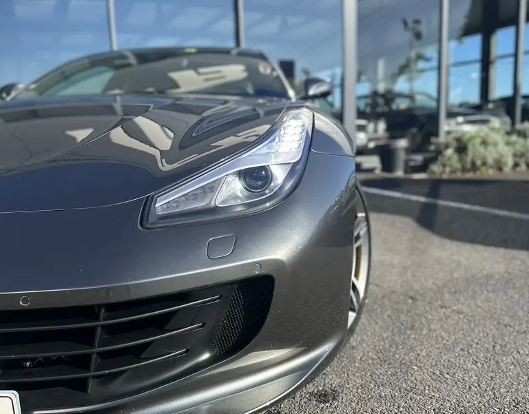 Vue 3/4 avant droit d'une Ferrari GTC4 Lusso gris foncé mettant en valeur son phare et la calandre sportive.