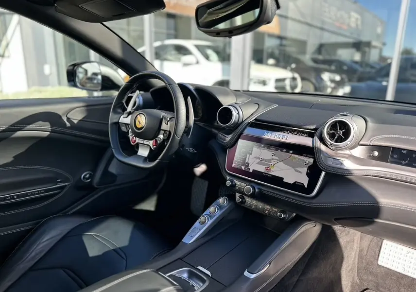 Intérieur noir de la Ferrari GTC4 Lusso 2017, vue côté conducteur avec volant sport et écran tactile central affichant la navigation.