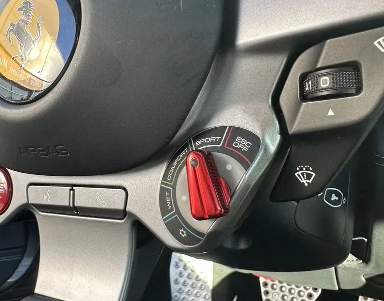 Vue rapprochée du volant de la Ferrari GTC4 Lusso gris foncé, mettant en valeur la molette de modes de conduite rouge.