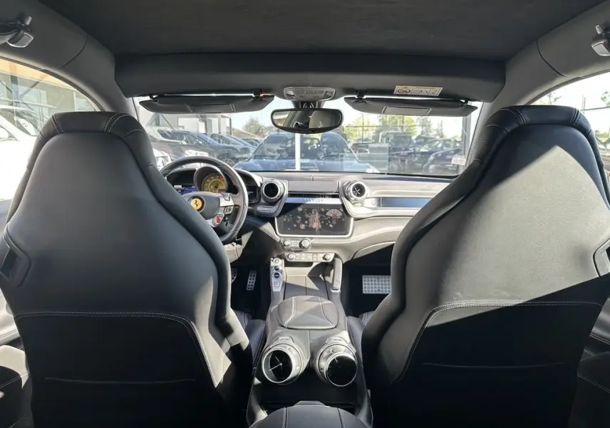 Vue intérieure avant de la Ferrari GTC4 Lusso gris foncé, avec sièges sport en cuir et tableau de bord moderne.