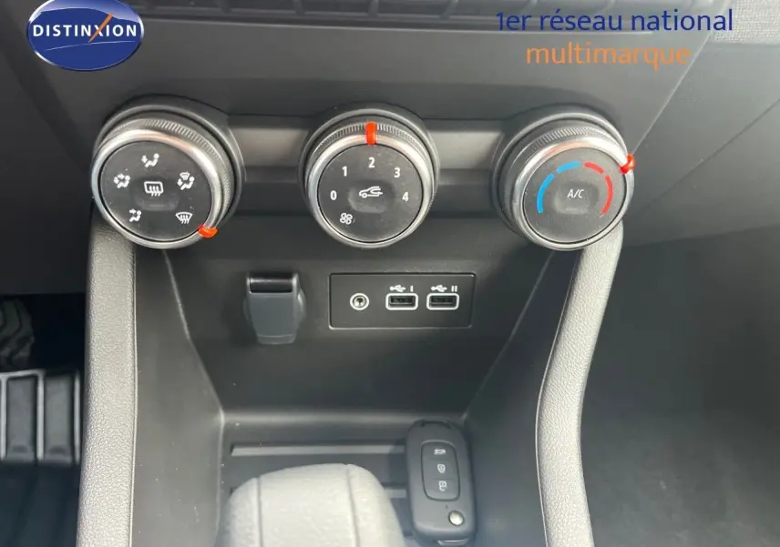 Gros plan sur la console centrale de la Renault Clio 2024 montrant les commandes de climatisation et ports USB.
