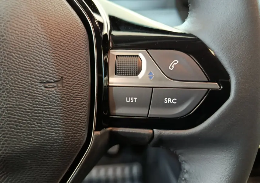 Gros plan sur les commandes du volant cuir noir de la Peugeot 208 PureTech 100 S&S Allure 2025.