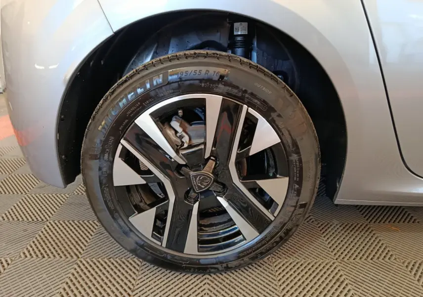 Gros plan sur la roue avant gauche gris clair de la Peugeot 208 2025 avec jante alliage noire et argentée.