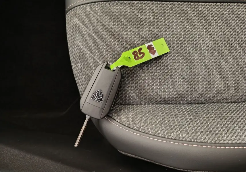Clé Peugeot posée sur le siège avant gris clair en tissu avec surpiqûres contrastantes, vue rapprochée intérieure.