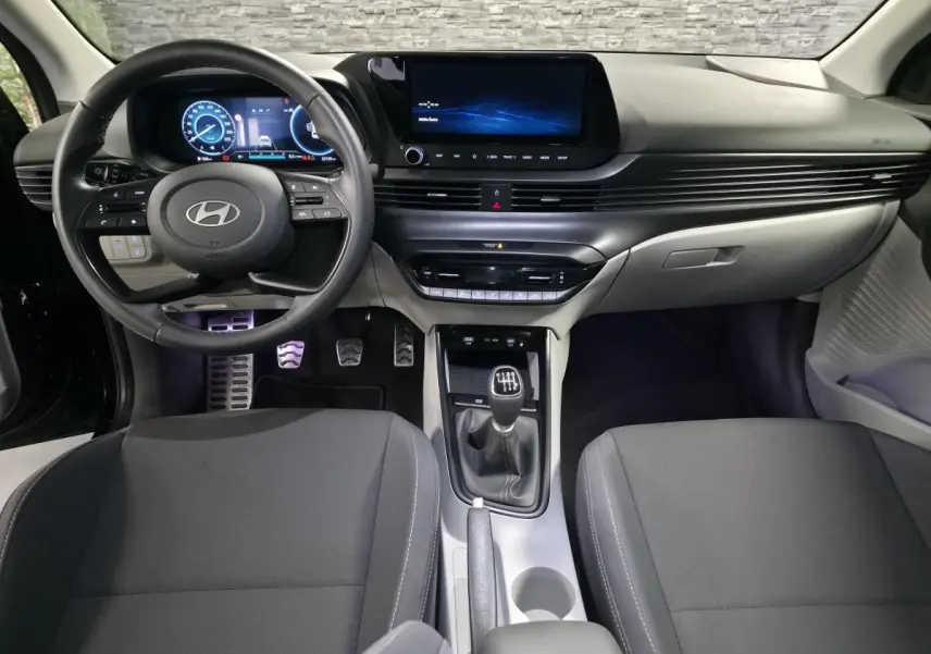 Vue intérieure avant du Hyundai Bayon 2025 essence noir, volant cuir, écran tactile et levier de vitesse manuel.