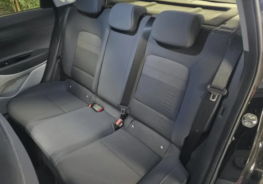 Vue intérieure des sièges arrière gris foncé du Hyundai Bayon 2025, avec ceinture de sécurité et porte ouverte côté droit.