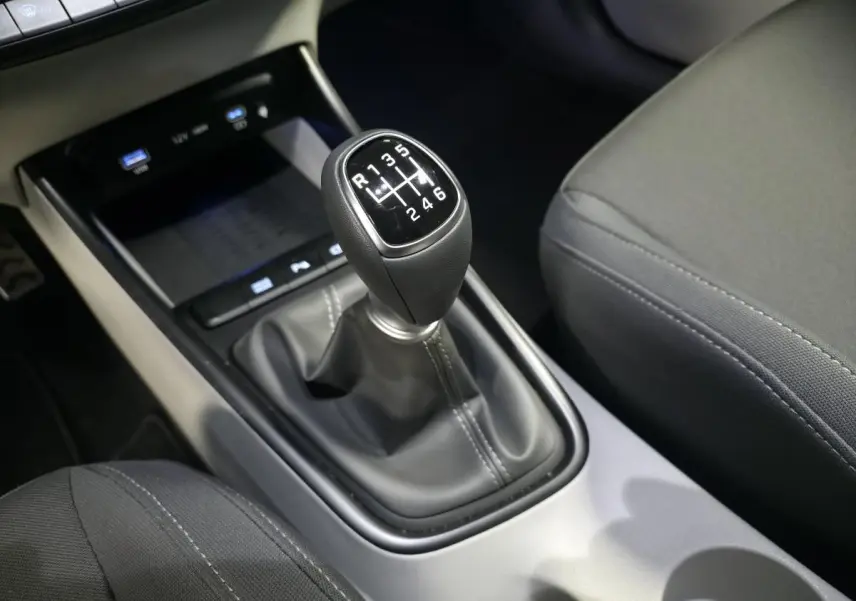 Gros plan sur le levier de vitesses manuel noir du Hyundai Bayon 2025, entouré de sièges tissu gris foncé.
