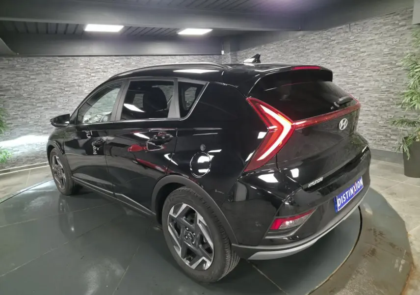 Vue 3/4 arrière droite d'une Hyundai Bayon noire métallisée avec feux arrière LED en forme de flèche.
