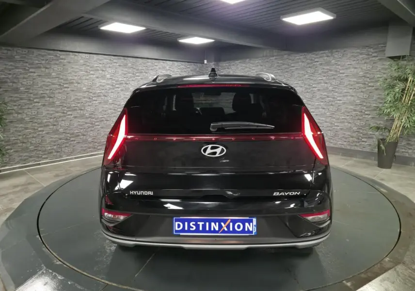 Vue arrière du Hyundai Bayon noir métallisé 2025 avec feux arrière LED allumés dans un showroom.