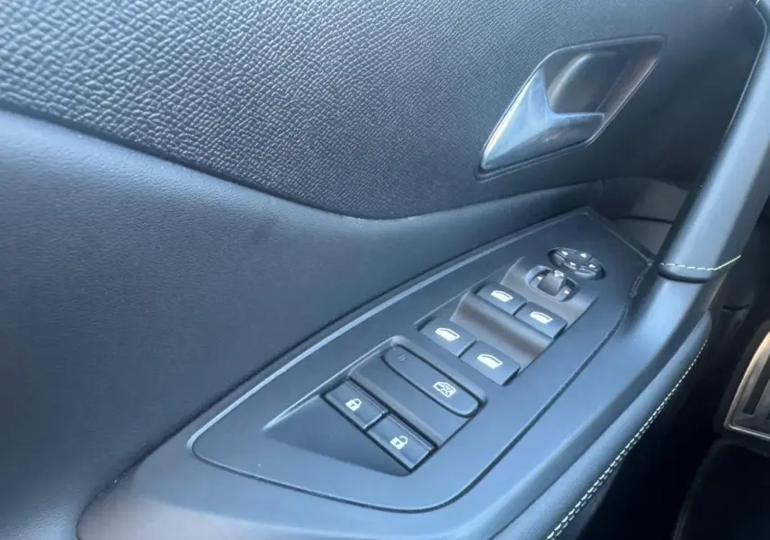 Vue rapprochée de la porte côté gauche de la Peugeot 408 Hybrid gris, montrant les commandes électriques des vitres et rétroviseurs.
