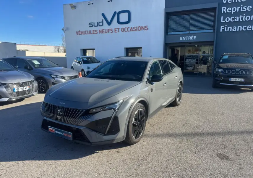 Peugeot 408 Hybrid gris vue 3/4 avant droit, jantes alliage 19 pouces et calandre distinctive au soleil.