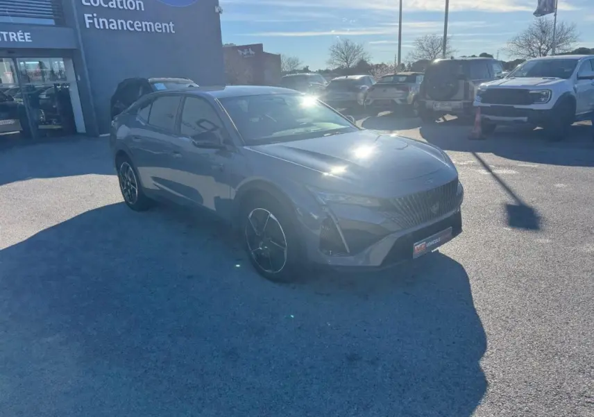 Peugeot 408 Hybrid gris en 3/4 avant droit, avec jantes alliage noires et calandre distinctive GT.