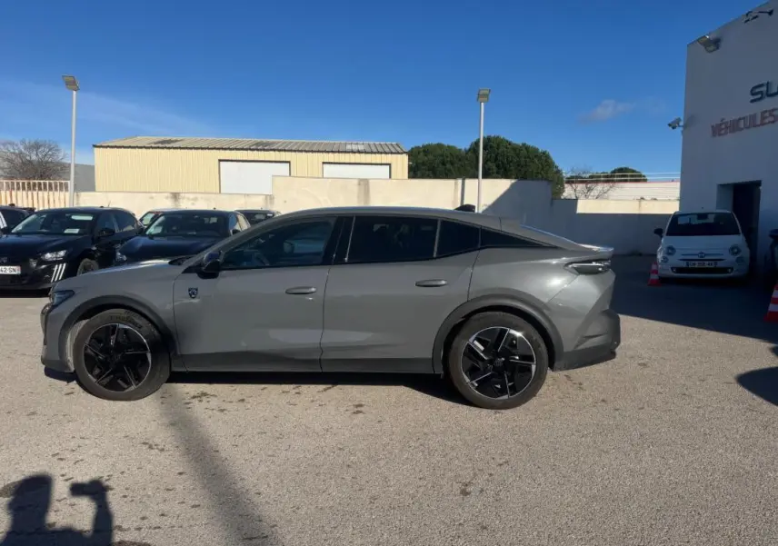 Vue de profil côté gauche d'une Peugeot 408 Hybrid 136 e-DCS6 GT gris avec jantes alliage noires de 19 pouces.