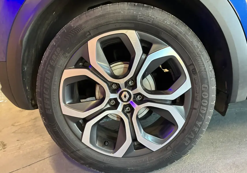 Gros plan sur la roue avant gauche d’un Renault Captur bleu 2021, mettant en valeur le pneu Goodyear et l’arche de roue noire.