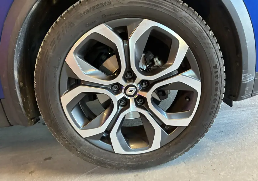 Gros plan sur la roue avant droite du Renault Captur bleu 2021, avec jante alliage au design moderne et logo central Renault.