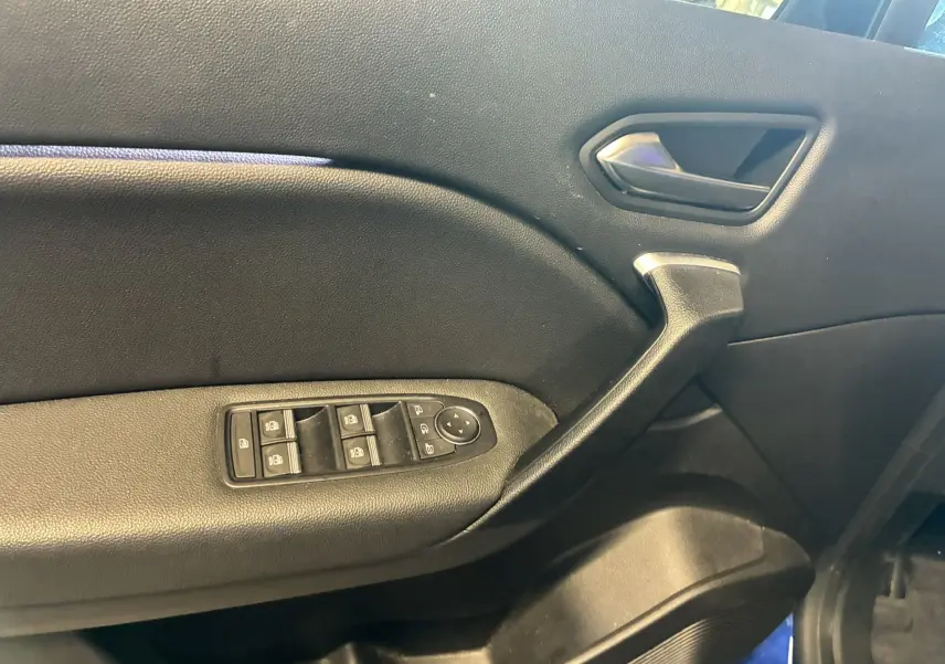Vue intérieure côté gauche de la porte avant d'un Renault Captur bleu, avec commandes électriques des vitres et poignée noire.
