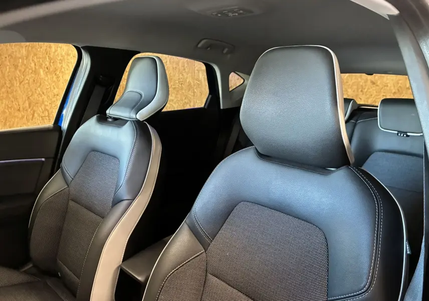 Vue intérieure des sièges avant en tissu noir avec surpiqûres blanches du Renault Captur bleu 1.3 TCE 140 Intens 2021.