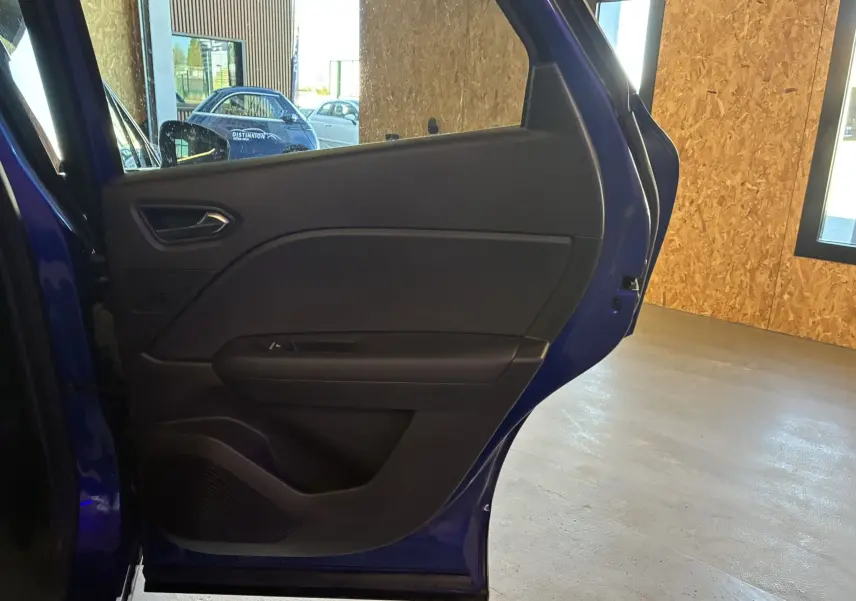 Vue latérale du côté gauche de la porte arrière ouverte du Renault Captur bleu, intérieur noir visible.