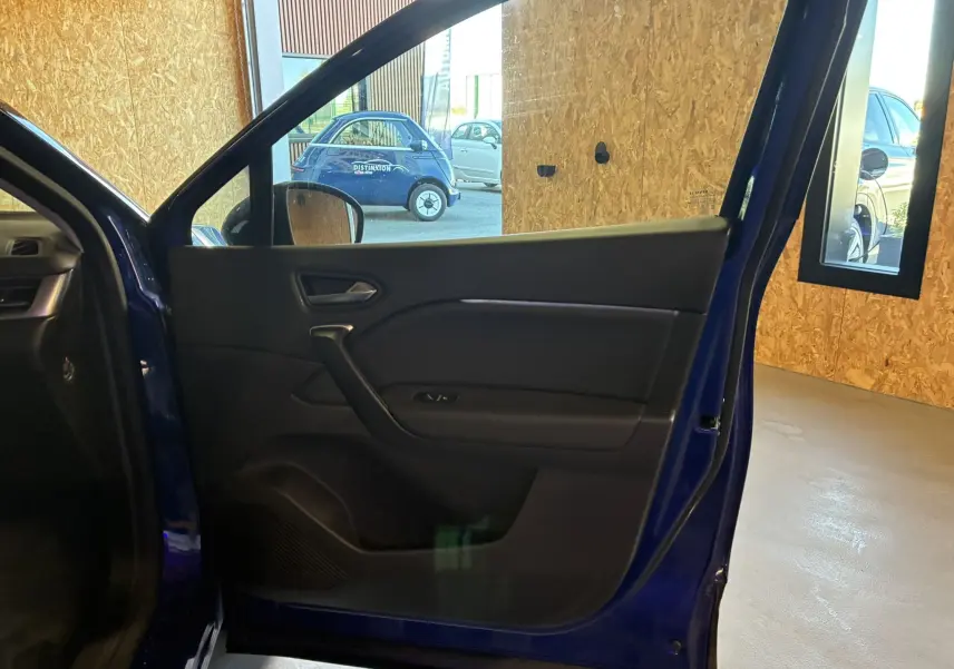 Vue intérieure de la porte avant gauche bleu du Renault Captur 1.3 TCE 140 Intens, avec poignée et commandes de vitre visibles.