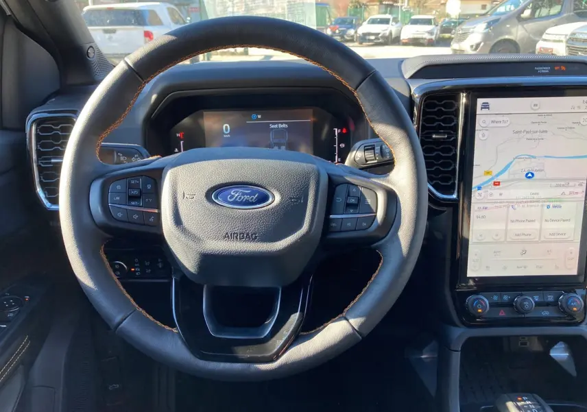 Vue frontale du volant cuir noir du Ford Ranger 2025 avec écran tactile vertical et tableau de bord numérique.