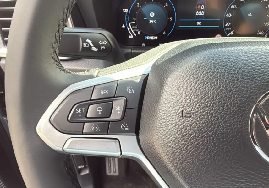 Gros plan sur le volant cuir multifonctions de la Volkswagen Amarok V6 240 BVA10 Aventura, avec commandes de régulateur.