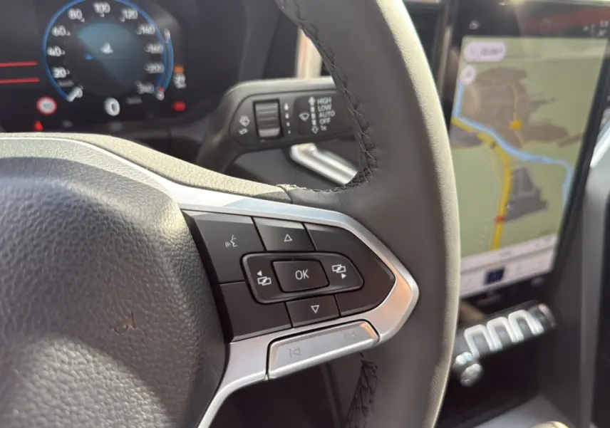 Gros plan sur le volant cuir multifonctions et l’écran tactile GPS du Volkswagen Amarok Simple Cabine gris foncé.