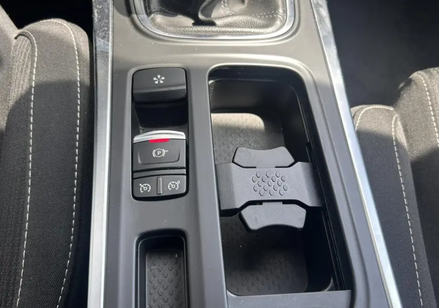 Vue rapprochée de la console centrale de la Renault Mégane IV Gris Titanium, montrant la commande de frein à main électrique et porte-gobelets.