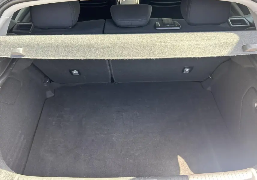 Coffre ouvert vu de l'arrière d'une Renault Mégane IV Gris Titanium, montrant l'espace de chargement vide.