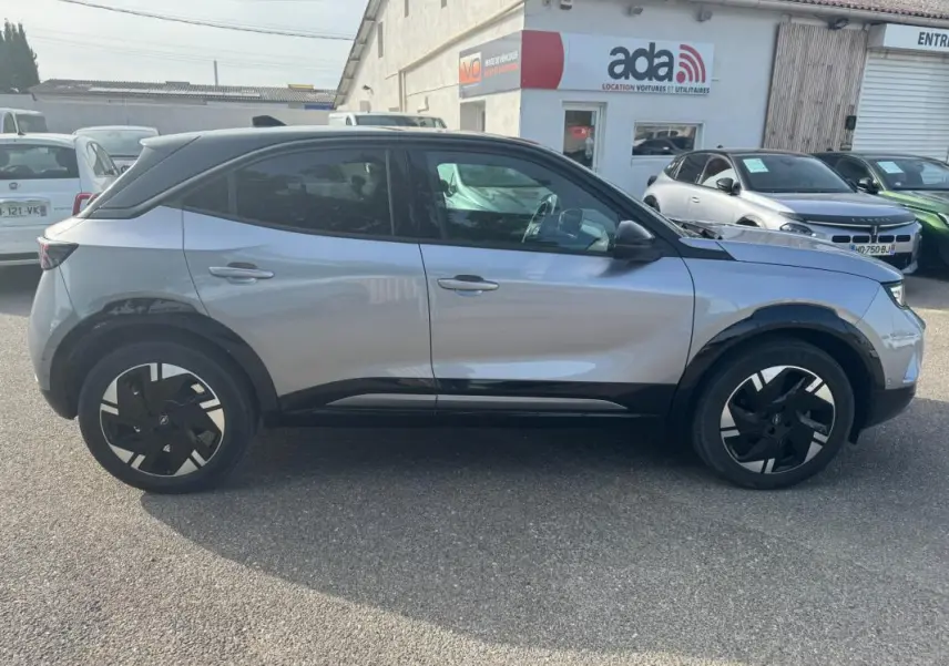 Vue latérale droite d’un Opel Mokka électrique gris 2025 avec jantes alliage noires et toit noir contrasté.