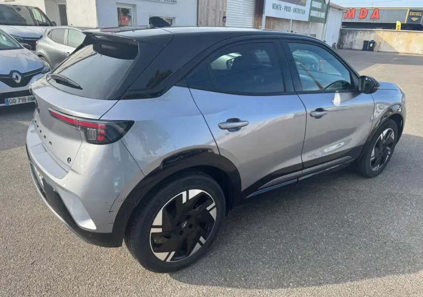 Vue 3/4 arrière droite d’un Opel Mokka électrique gris avec toit noir, jantes alliage 17 pouces et vitres surteintées.