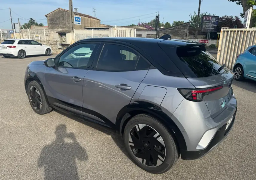 Opel Mokka électrique gris en vue 3/4 arrière droit, avec jantes alliage noires et vitres surteintées.