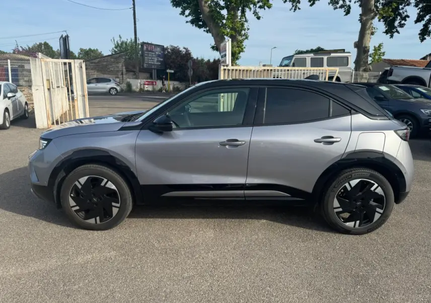 Vue de profil côté gauche d'un Opel Mokka électrique gris avec jantes alliage noires et vitres surteintées.