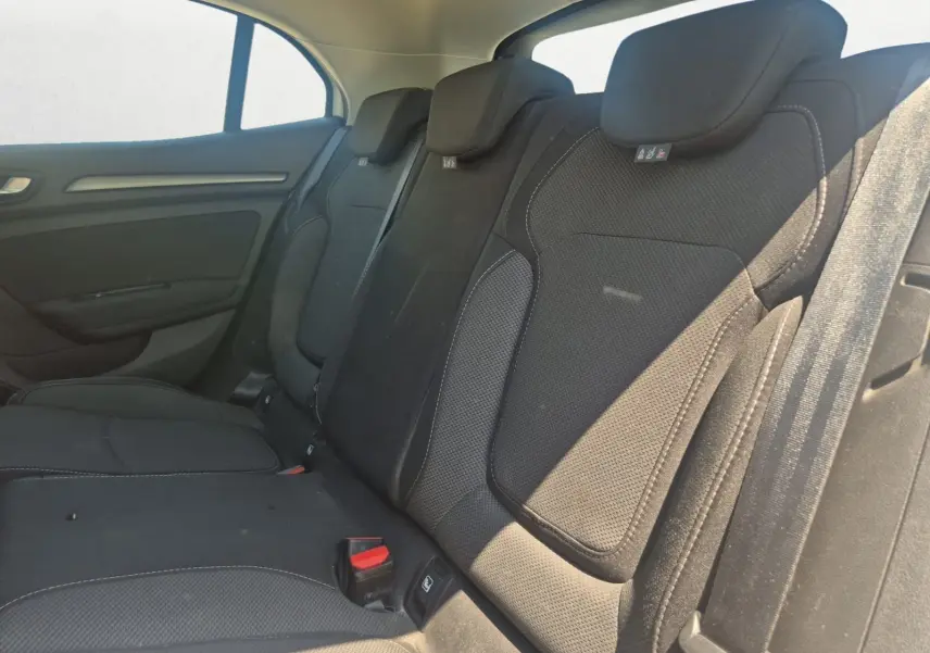 Vue intérieure côté conducteur de la Renault Mégane blanche 2022, montrant les sièges noirs et le volant multifonction.