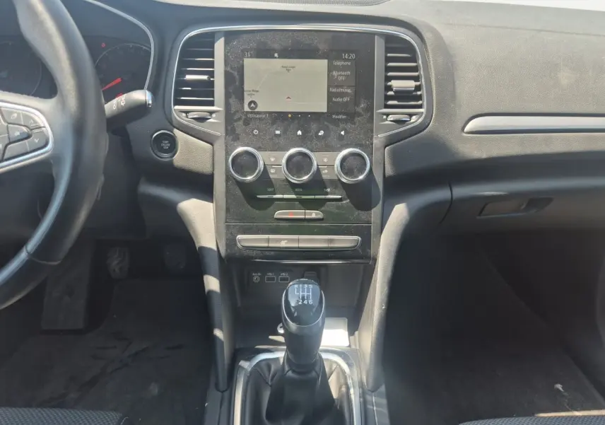 Vue intérieure centrée sur le volant noir de la Renault Mégane blanche 2022 avec tableau de bord et écran tactile visibles.