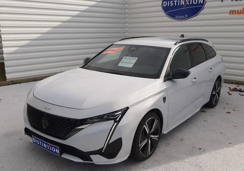 Peugeot 308 SW blanc Okenite vue 3/4 avant droit, avec calandre noire et jantes alliage bicolores.