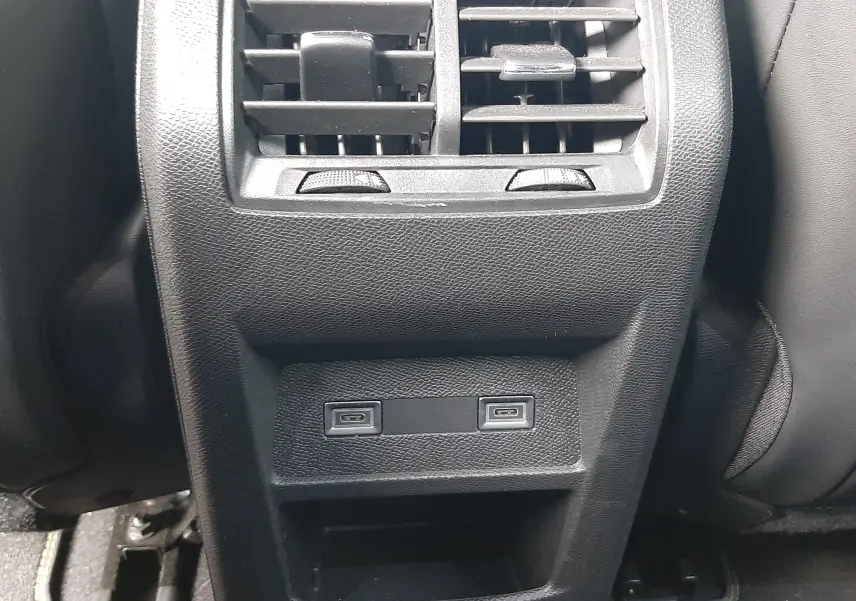 Vue rapprochée de la console arrière noire du Peugeot 308 SW 2024 avec bouches d’aération et deux ports USB.
