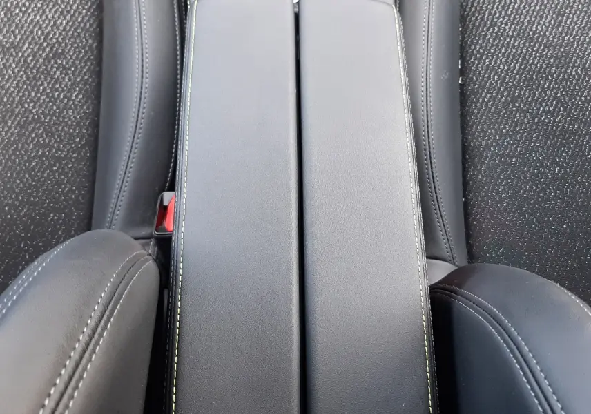 Gros plan sur l'accoudoir central noir avec surpiqûres contrastantes dans l'habitacle d'une Peugeot 308 SW.
