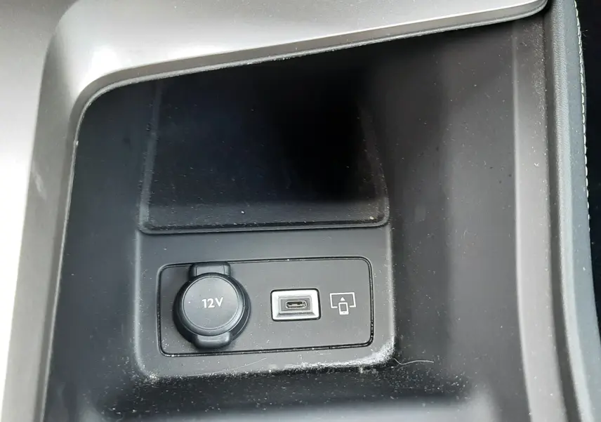 Gros plan sur la prise 12V et port USB dans la console centrale noire du Peugeot 308 SW 2024.