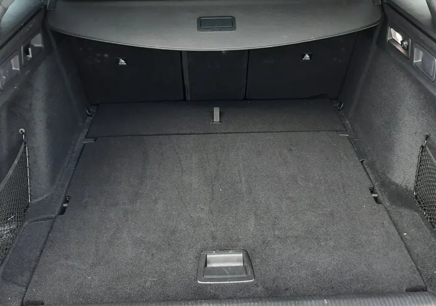 Vue intérieure du coffre spacieux et noir du Peugeot 308 SW 2024, avec banquette arrière et tablette cache-bagages visibles.