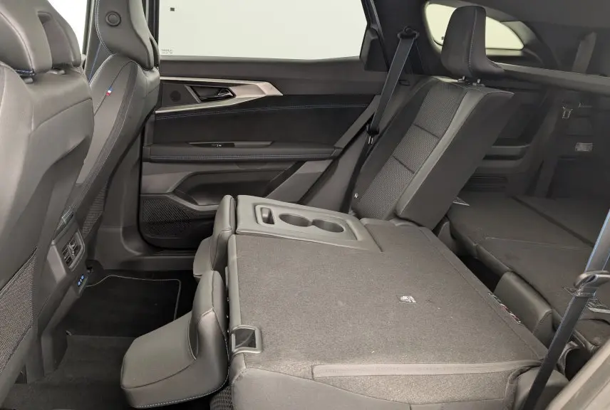 Vue latérale intérieure côté droit du Renault Espace gris Schiste, sièges arrière partiellement rabattus avec accoudoir central visible.