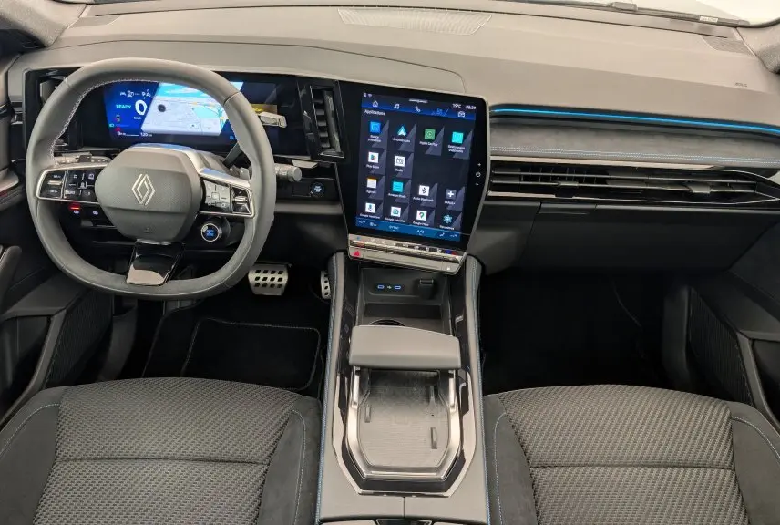 Vue intérieure avant du Renault Espace E-Tech gris avec tableau de bord numérique et écran tactile vertical lumineux.