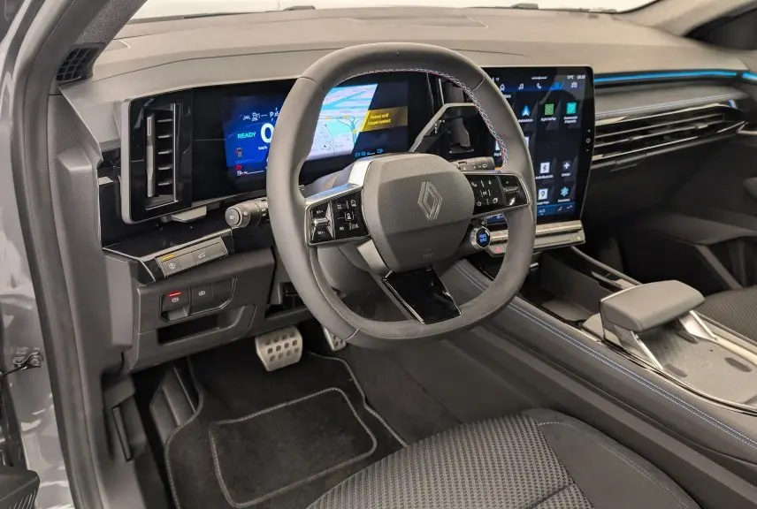 Vue intérieure côté conducteur du Renault Espace E-Tech gris avec tableau de bord numérique et volant multifonction à surpiqûres bleues