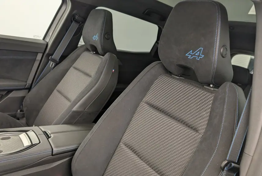 Gros plan sur les sièges avant en tissu carbone et alcantara gris avec surpiqûres bleues et logo Alpine brodé sur appuie-tête.